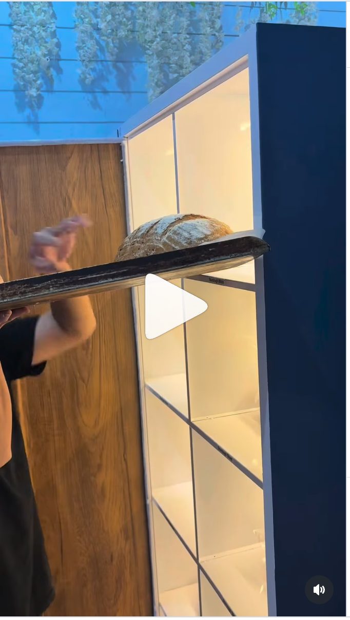 Baked by Keiran staff member loading a fresh loaf into the Bread Wall from the bakery side